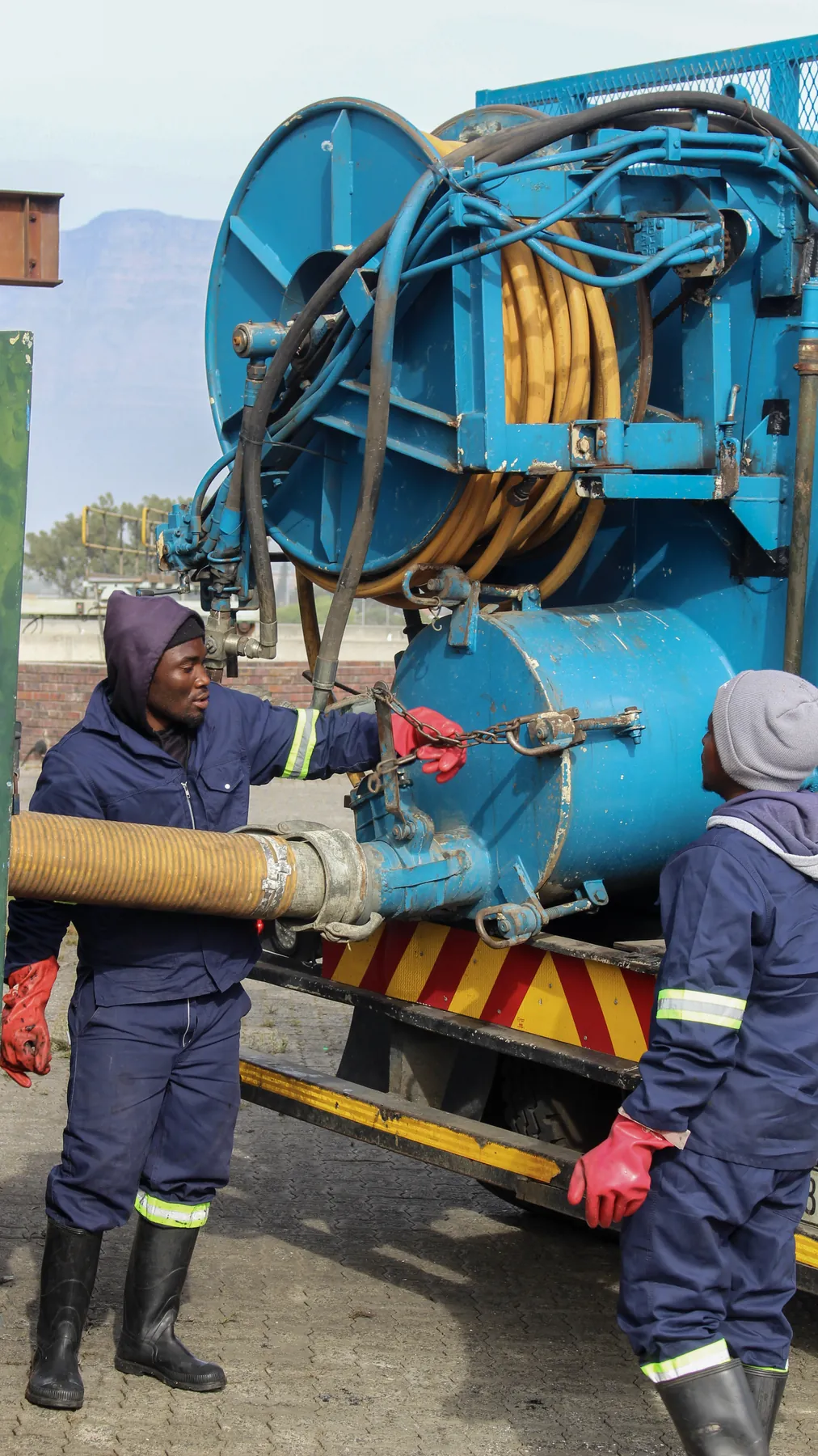 Crew member connecting the suction line at the back of a tanker