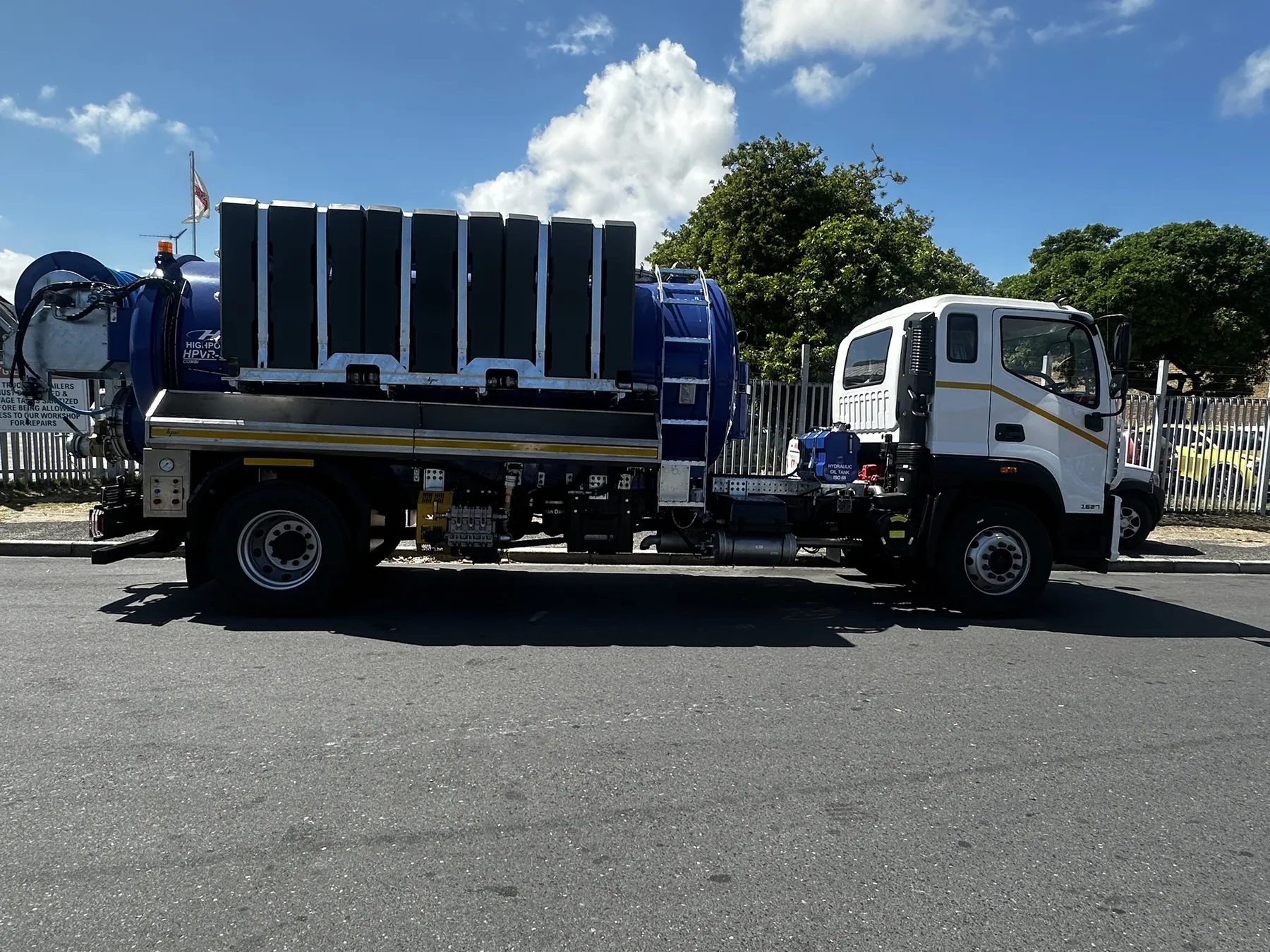 Combination super sucker parked on a street, white cab and blue tank