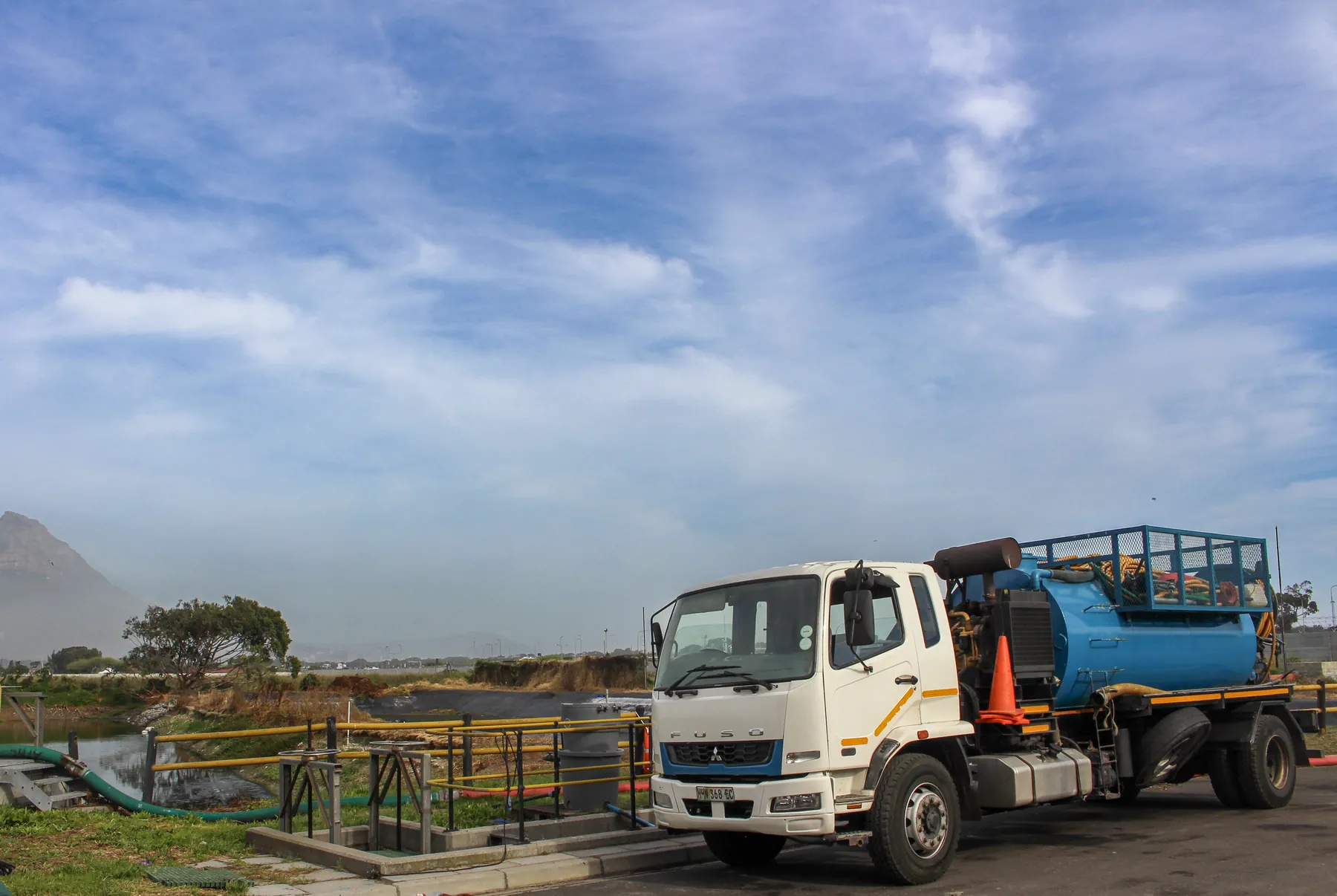 Vacuum tanker parked beside a treatment works with mountains behind