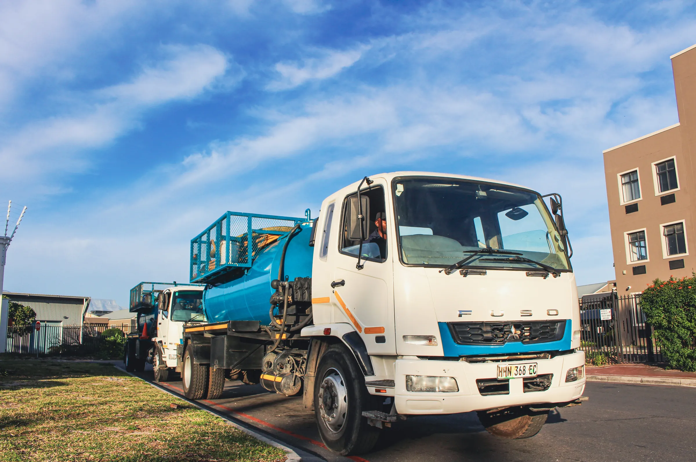 White Fuso cab with a blue vacuum tank under a blue sky