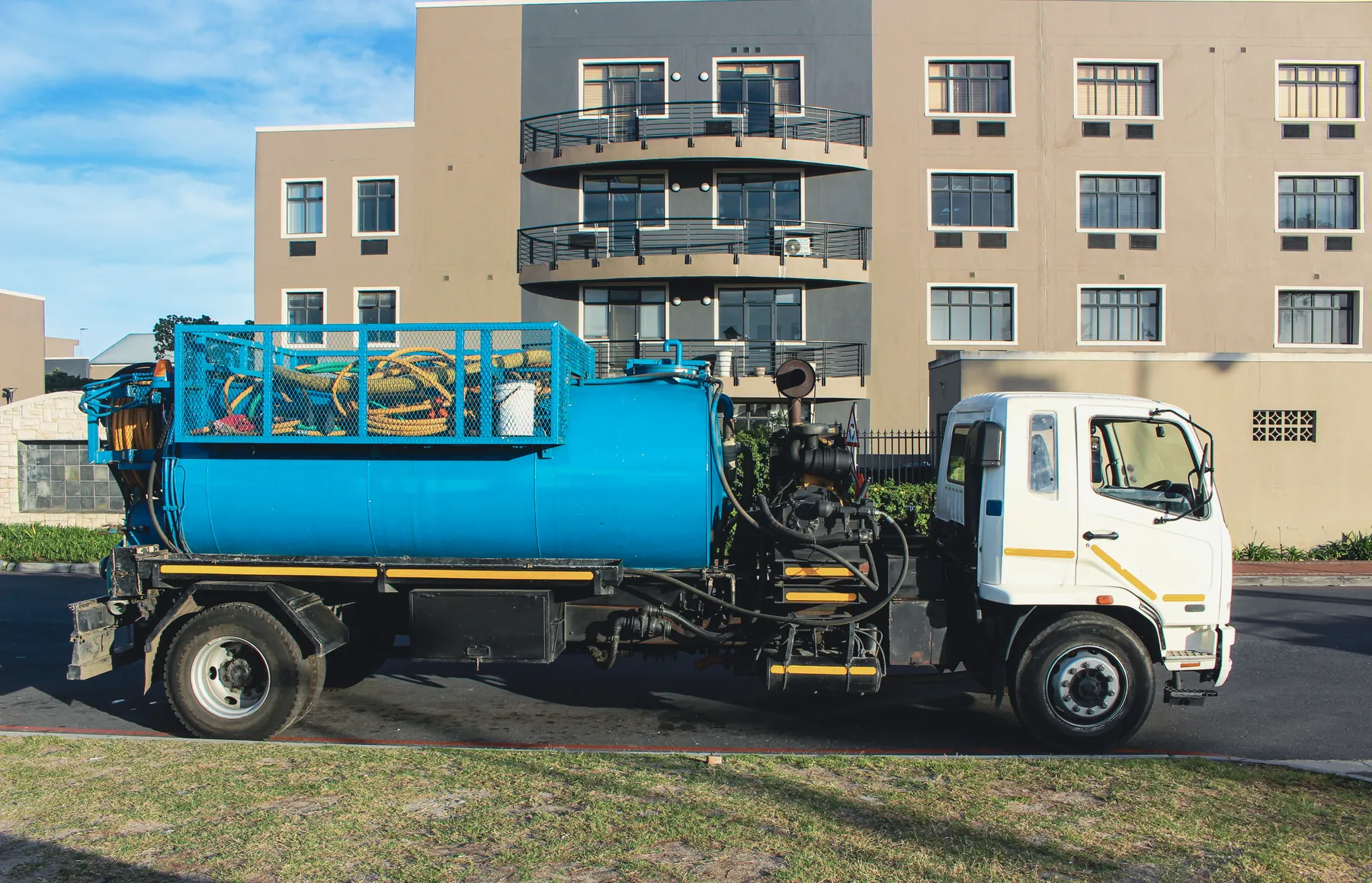 Side view of a Ramatini vacuum tanker in front of an apartment building